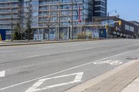 an empty street with white arrows painted on the ground next to a shopping mall in a city