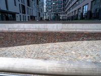 a paved area in front of buildings on the side of a sidewalk that looks like cobbles