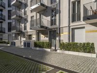 modern apartment buildings with balconies and an empty cobblestone road in the sun