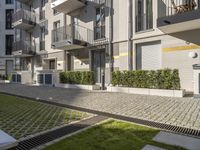 modern apartment buildings with balconies and an empty cobblestone road in the sun