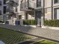 modern apartment buildings with balconies and an empty cobblestone road in the sun