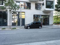 small car parked next to sidewalk in front of building with cafe window sign that reads ely