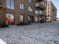 some buildings that are next to each other on street bricks in front of a couple of windows