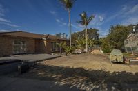 a view of a yard with some plants in the back ground and a house and building behind