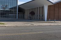 a brick and glass building sits outside of the middle school, with grass on the ground