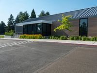 a building that has windows and plants in the front yard of it, in the middle of a gravel parking lot