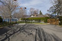 there is a black iron fence near the road that leads into a house with a large gate