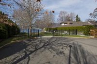 there is a black iron fence near the road that leads into a house with a large gate