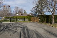 there is a black iron fence near the road that leads into a house with a large gate