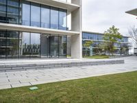 a person sitting on a bench in a building with glass windows and a lawn area