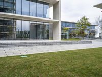 a person sitting on a bench in a building with glass windows and a lawn area