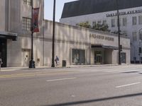 there are people walking on the side of the road in front of a large building