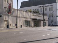 there are people walking on the side of the road in front of a large building