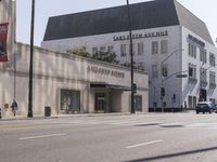 there are people walking on the side of the road in front of a large building