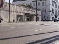 there are people walking on the side of the road in front of a large building