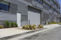 a building on the side of the street near a parking lot with plants growing in it