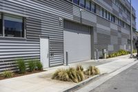 a building on the side of the street near a parking lot with plants growing in it