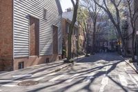 a crosswalk is near a tree and building with tall windows in the background of this residential area