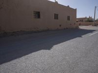 an empty street in front of a building and a sunlit doorway to the other side
