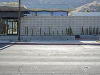 a stop sign on the corner next to a road with hills in the background and a building that looks like a cactus plant