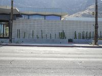 a stop sign on the corner next to a road with hills in the background and a building that looks like a cactus plant