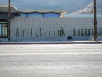 a stop sign on the corner next to a road with hills in the background and a building that looks like a cactus plant