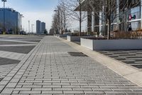 a empty sidewalk beside the curb where there are a lot of parked cars and a building