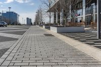 a empty sidewalk beside the curb where there are a lot of parked cars and a building