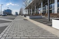 a empty sidewalk beside the curb where there are a lot of parked cars and a building