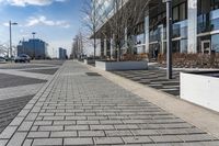 a empty sidewalk beside the curb where there are a lot of parked cars and a building