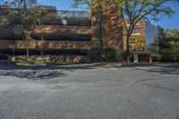 a parking garage is shown at an intersection in a city street corner with trees on either side and a large brick building in the background