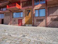 a brick paved area with red shutters and garage doors and windows, in a residential area