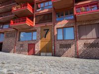 a brick paved area with red shutters and garage doors and windows, in a residential area