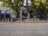 a fire hydrant on the corner near a gray building, while a yellow fire hydrant stands at the end