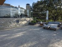 a backyard with a gravel path and lawn furniture set up beside a stone wall and large glass patio