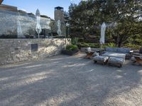 a backyard with a gravel path and lawn furniture set up beside a stone wall and large glass patio