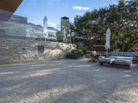 a backyard with a gravel path and lawn furniture set up beside a stone wall and large glass patio