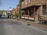 an empty street in front of a row of brick houses with an awning and front porch