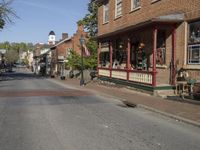 an empty street in front of a row of brick houses with an awning and front porch