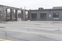 the empty parking lot has only snow on the ground in front of an old brick factory