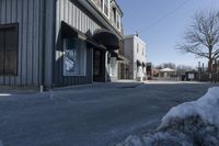 an empty street that is blocked off by snow on the ground in front of a store