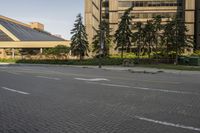 the paved street in front of an urban building is empty of cars, and a couple pedestrians have stopped on one side