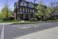 an empty street in front of a large house with bikes written on the sidewalk, in front of houses with trees