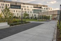 a city street surrounded by grass and tall buildings at the end of a street there is a paved pathway in front of the building