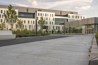 a city street surrounded by grass and tall buildings at the end of a street there is a paved pathway in front of the building