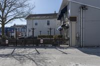 a fenced in parking lot with a house in the background and cars on it