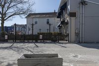 a fenced in parking lot with a house in the background and cars on it