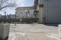 a fenced in parking lot with a house in the background and cars on it