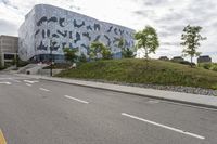 an empty street lined with road markers on a hill in front of a modern building