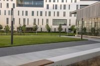 a city street surrounded by grass and tall buildings at the end of a street there is a paved pathway in front of the building